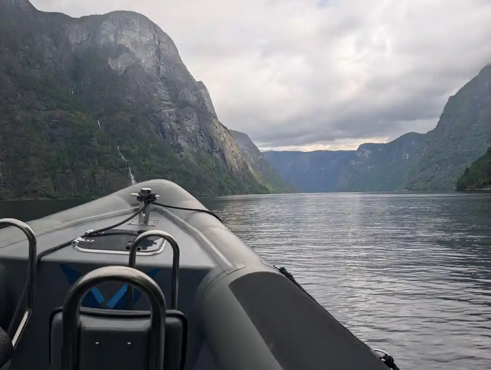 The boat running down the fjord under a pale sky