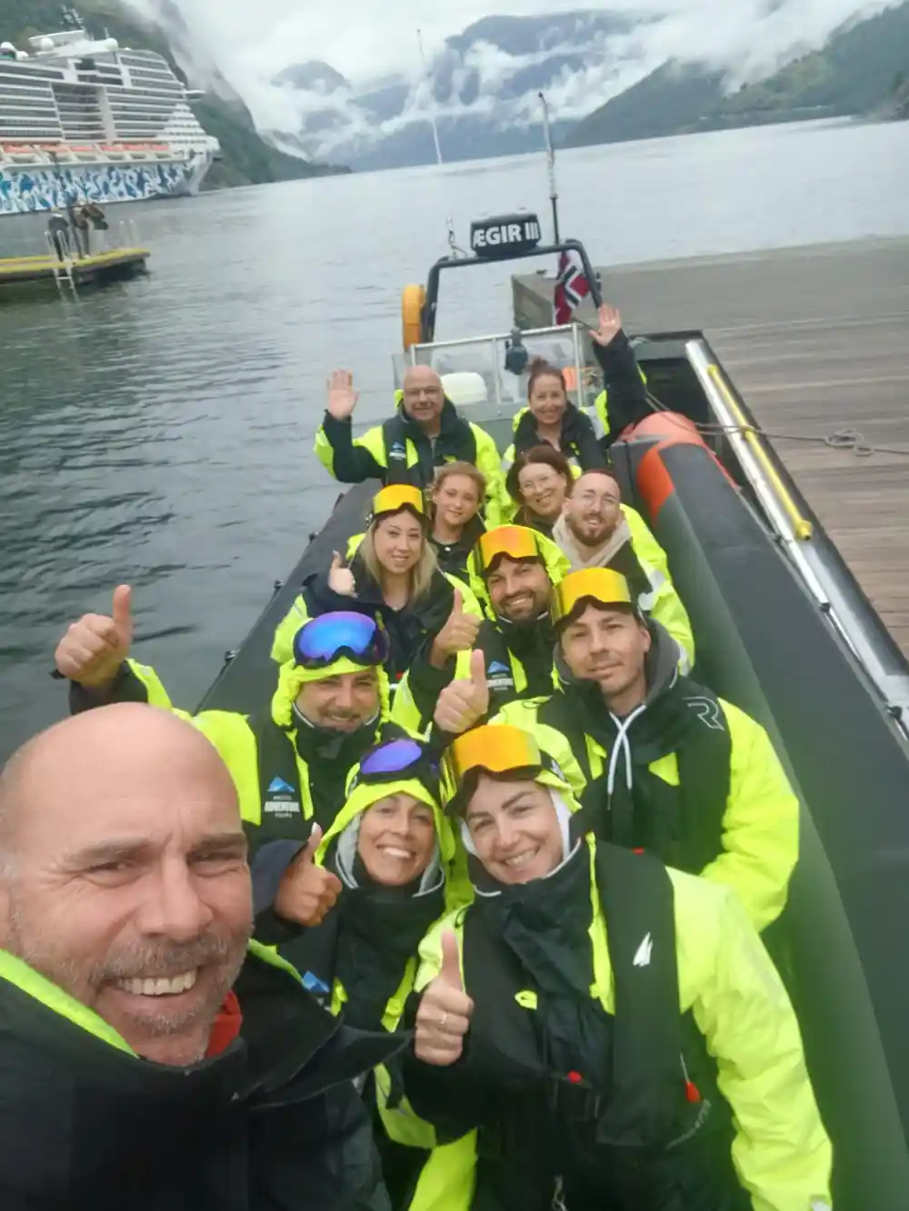 A boatload of passengers in suits and goggles giving a thumbs up