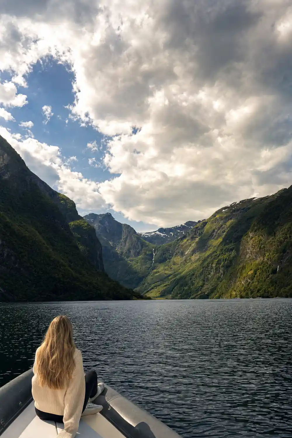 Cloud sitting low on a green mountainside above the fjord