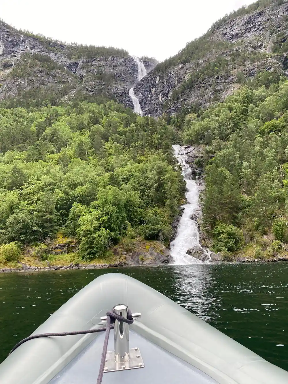 A long waterfall dropping through trees to the water