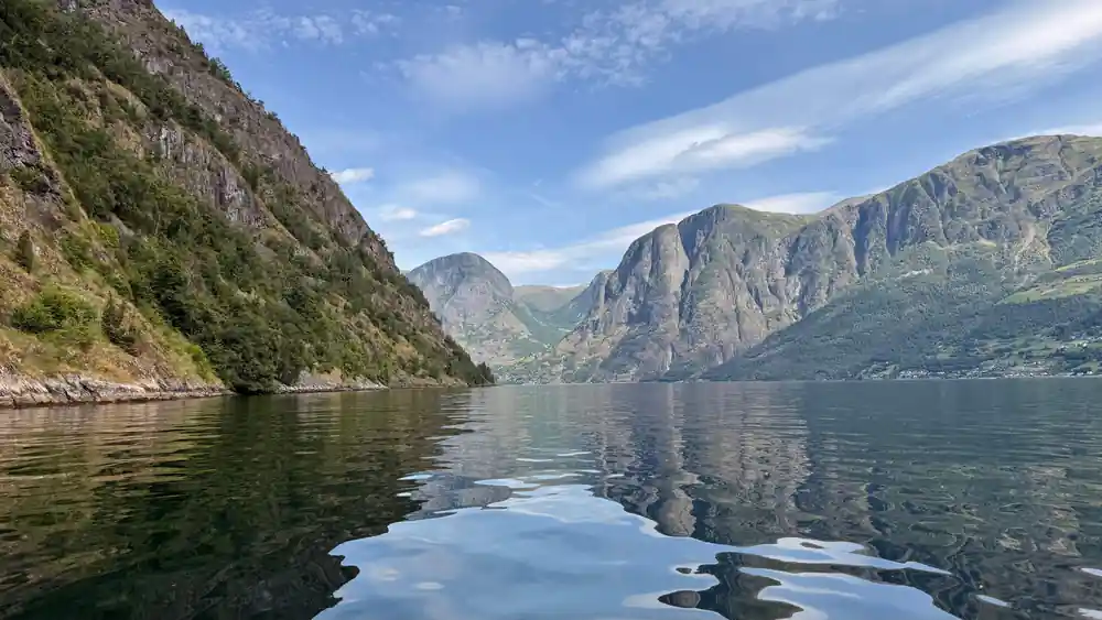 Mirror-flat water between two walls under a blue sky