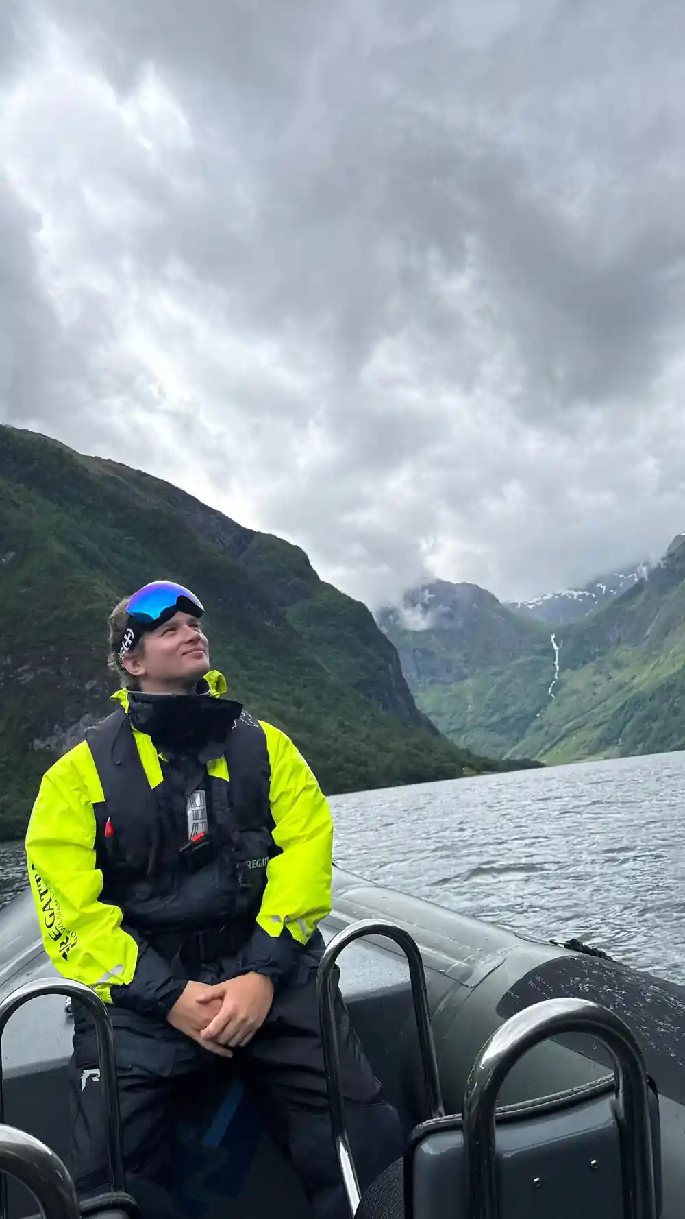 A passenger in a survival suit looking up at the fjord walls