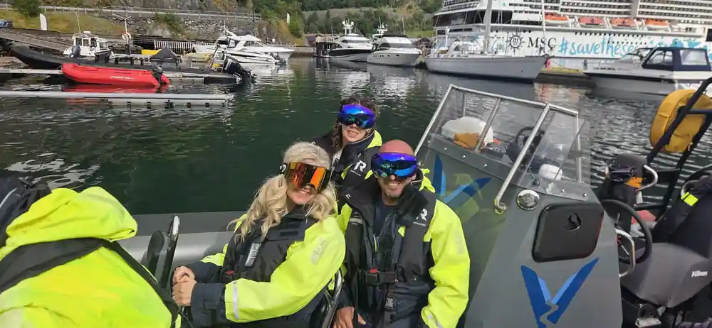 Passengers in goggles at the marina with boats moored behind
