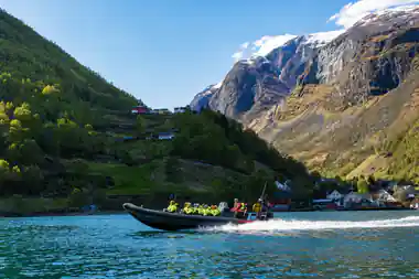 The RIB running fast past a village below a steep green mountain