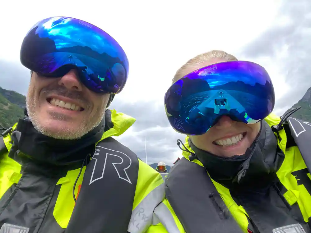 Two passengers in goggles and survival suits close to the camera