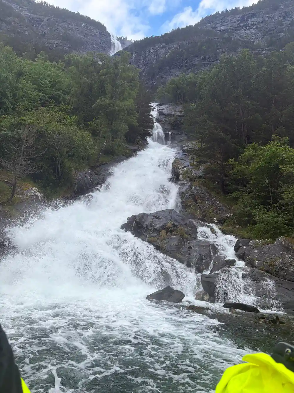 A waterfall breaking white over boulders into the fjord