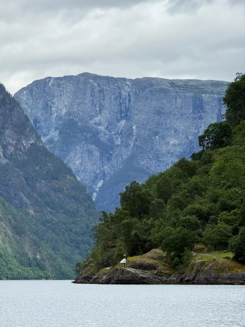 A wooded spur below a pale grey cliff face rising from the water